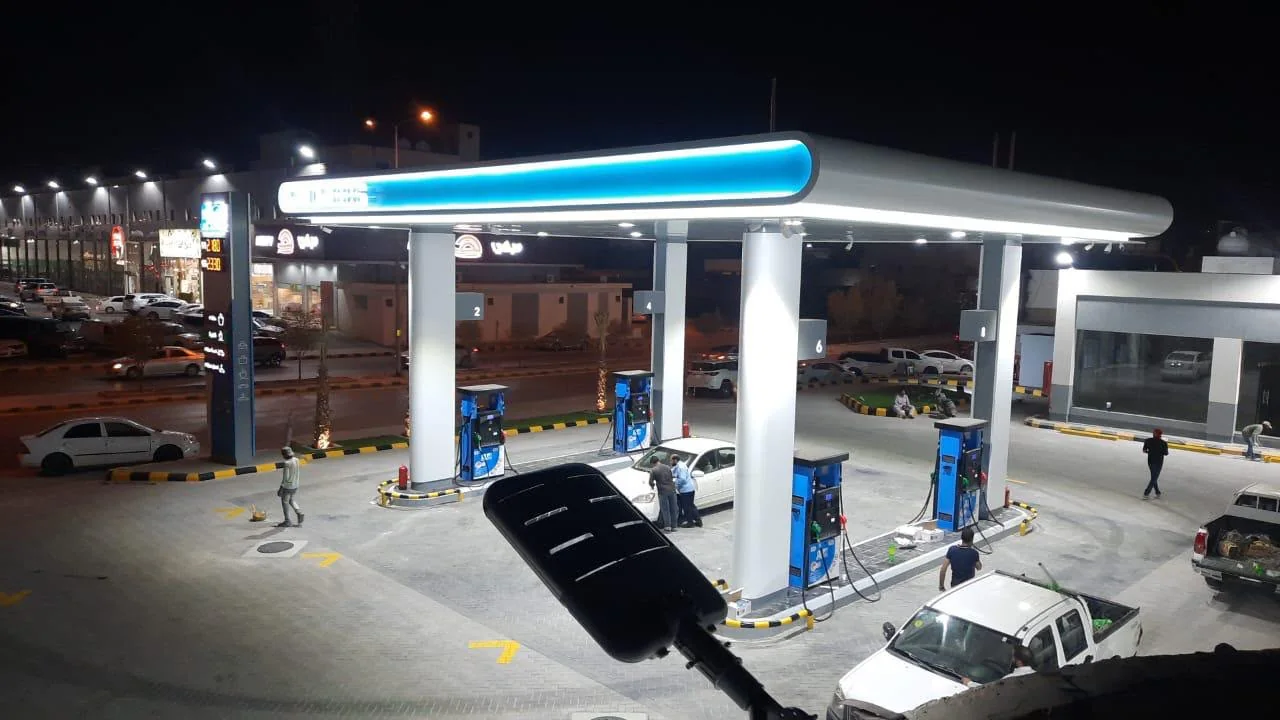 Night view of a completed commercial forecourt with canopy lighting and pylon signage